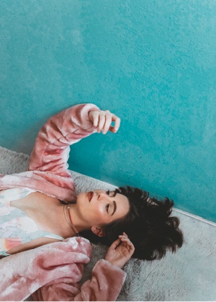 woman laying on bed with pink jacket looking up