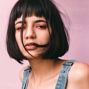 Woman with pink backdrop and short dark hair